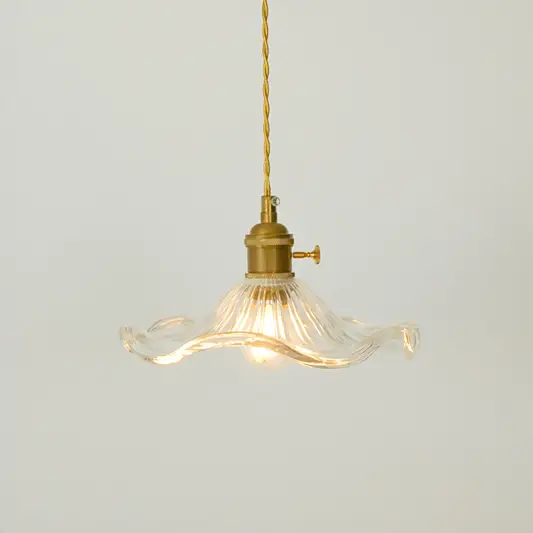 A vintage-style pendant light with a clear ribbed glass shade that has wavy, flared edges and a brass metal fixture, suspended from a brass cord against a light gray background.