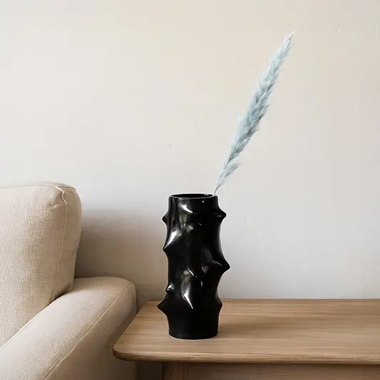 Black sculptural vase with dried stem styled on console table adding bold artistic contrast to modern home Decor.