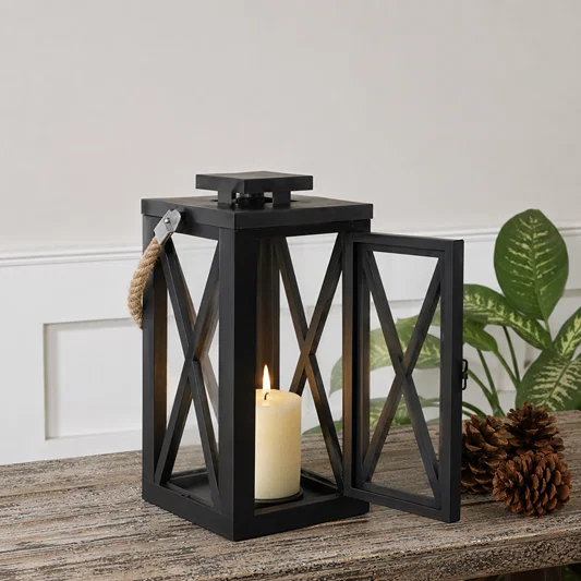 Modern black metal candle lantern with cross frame design adding decorative ambient lighting to outdoor living spaces.