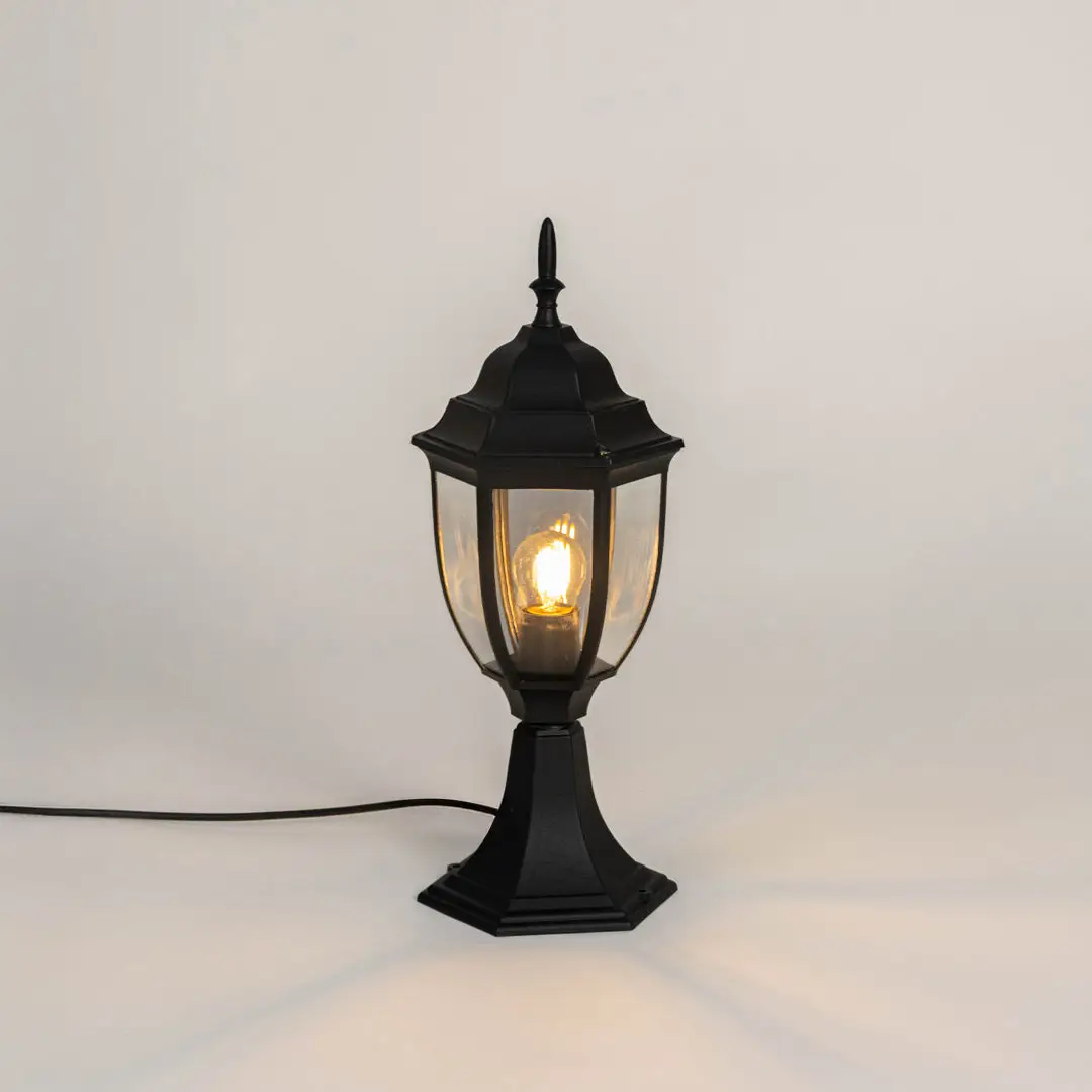 Black metal outdoor gate light with glowing bulb and clear glass shade for modern decor use.