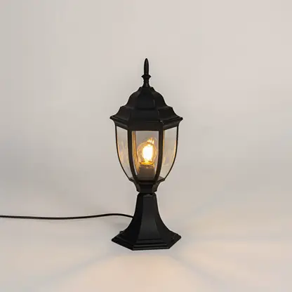 Black metal outdoor gate light with glowing bulb and clear glass shade for modern decor use.