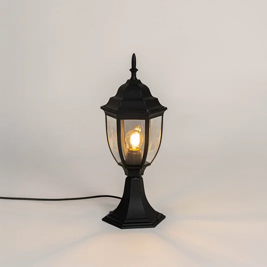 Black metal outdoor gate light with glowing bulb and clear glass shade for modern decor use.