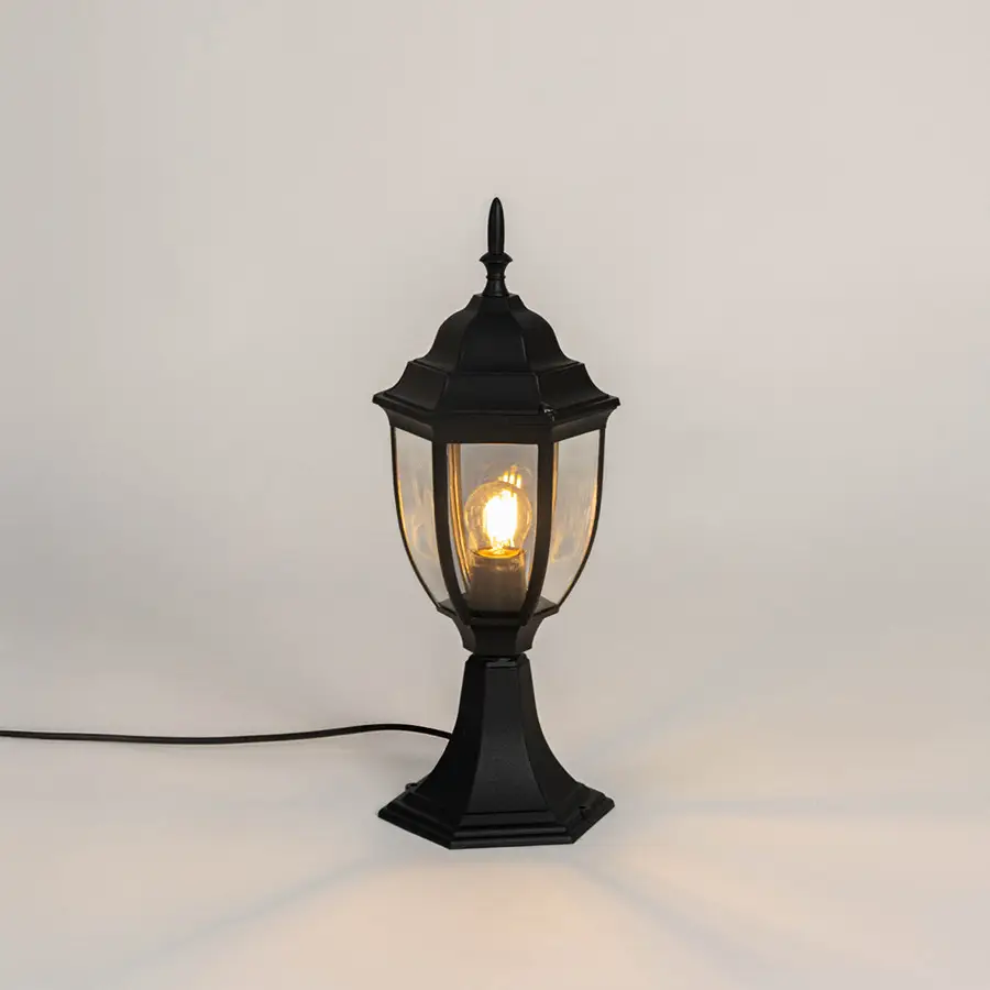 Black metal outdoor gate light with glowing bulb and clear glass shade for modern decor use.