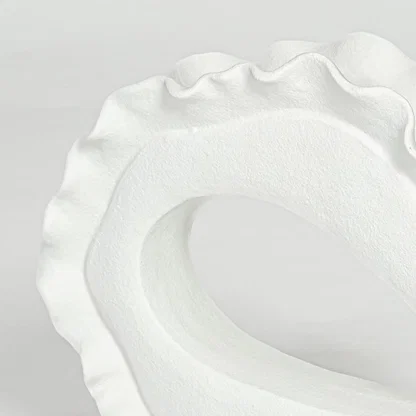 Closeup of white ceramic decorative bowl with organic sculptural form highlighting refined handcrafted texture and design.