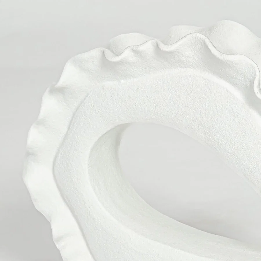 Closeup of white ceramic decorative bowl with organic sculptural form highlighting refined handcrafted texture and design.