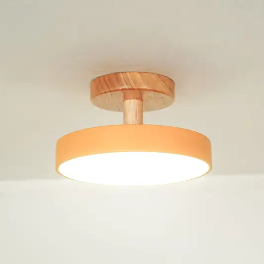 Closeup of peach metal and natural wood ceiling light for contemporary bedroom and Scandinavian decor styling spaces.
