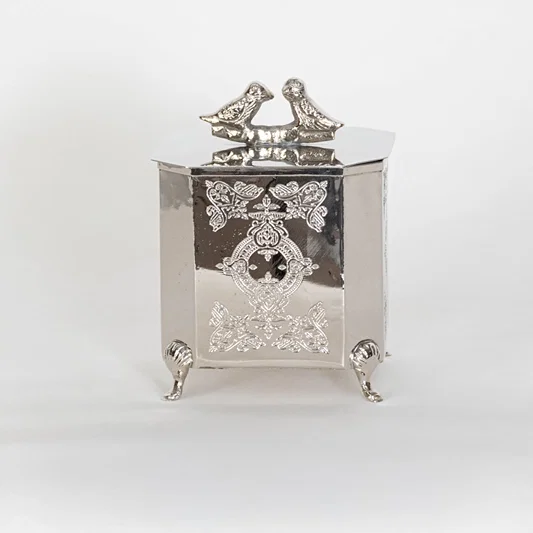 Classic silver metal trinket box with raised patterns and bird top on white background perfect for elegant home Decor.