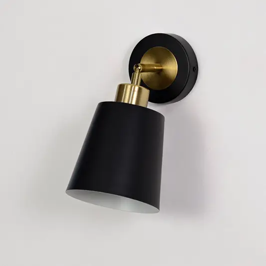 Black metal wall sconce with gold arm turned off on a white background showcasing clean finish premium material and modern design.