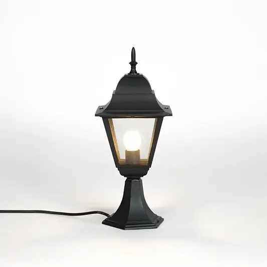 Black outdoor gate light with warm glowing bulb and clear glass shade for elegant exterior decor use.
