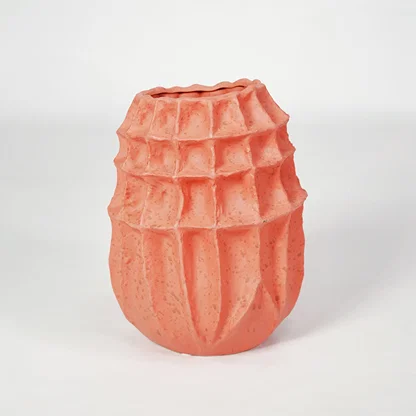 Pink textured ceramic vase for modern shelf placement and artistic indoor living room decor styling accent piece.