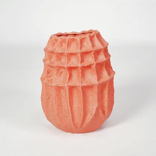 Pink textured ceramic vase for modern shelf placement and artistic indoor living room decor styling accent piece.