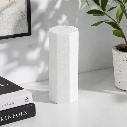 White textured ceramic vase placed on shelf beside books for elegant modern home decor styling.