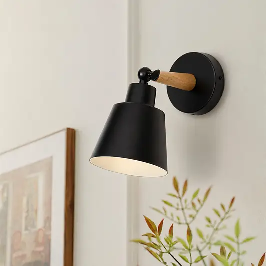 Modern wall light installed above a wooden sideboard creating a warm ambient glow that enhances a calm living space with soft decor textures and minimalist styling.