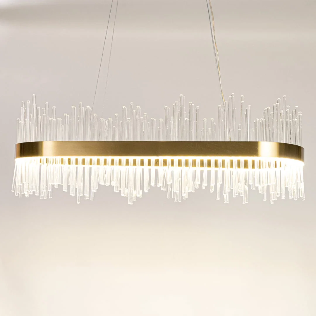 Gold metal chandelier with clear glass rods shown with lights on against a white background highlighting its bright elegant illumination.