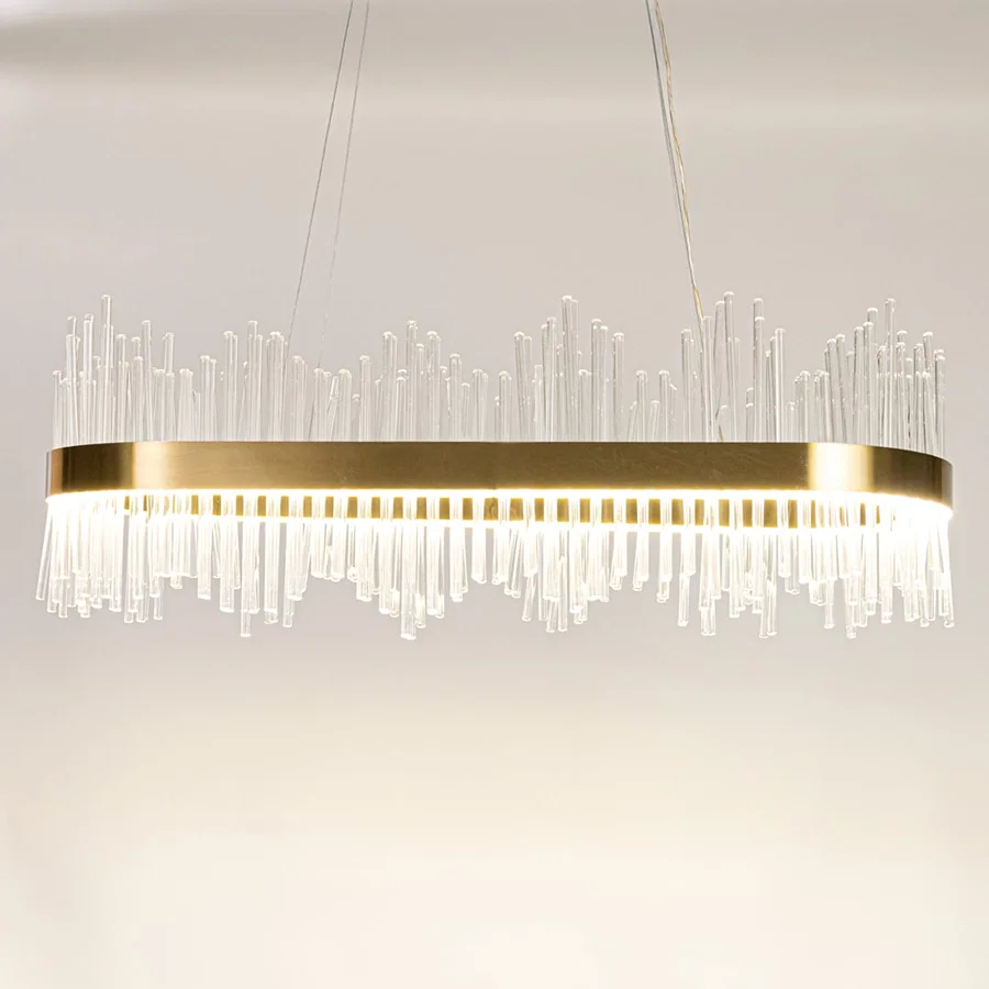 Gold metal chandelier with clear glass rods shown with lights on against a white background highlighting its bright elegant illumination.