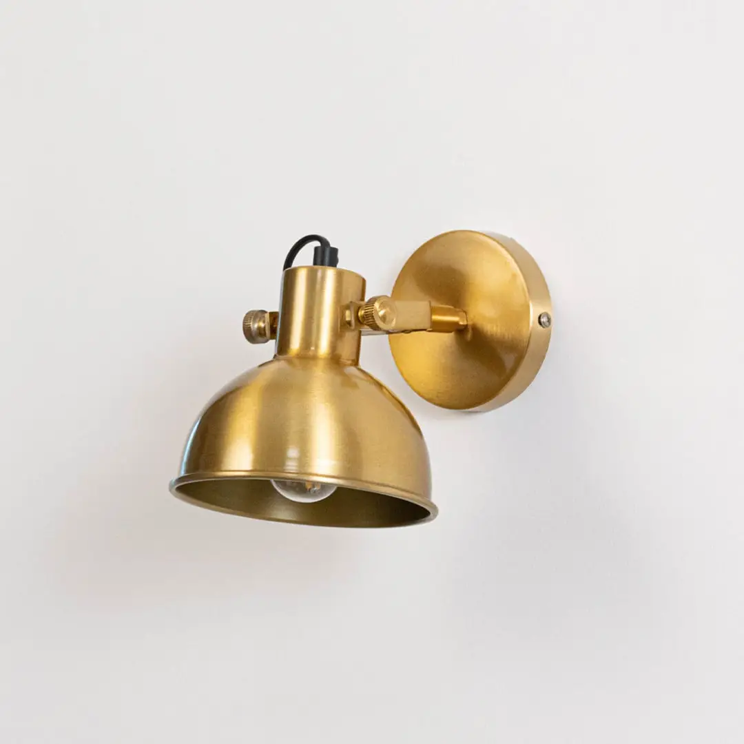 Gold metal wall mounted light switched off on white background emphasizing minimal form and elegant metallic finish.
