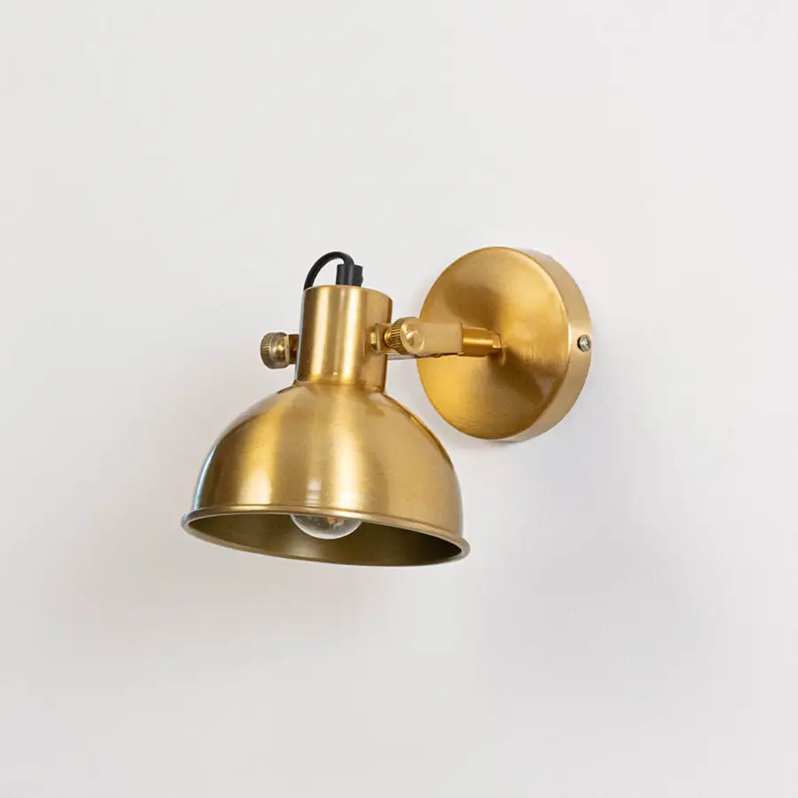 Gold metal wall mounted light switched off on white background emphasizing minimal form and elegant metallic finish.