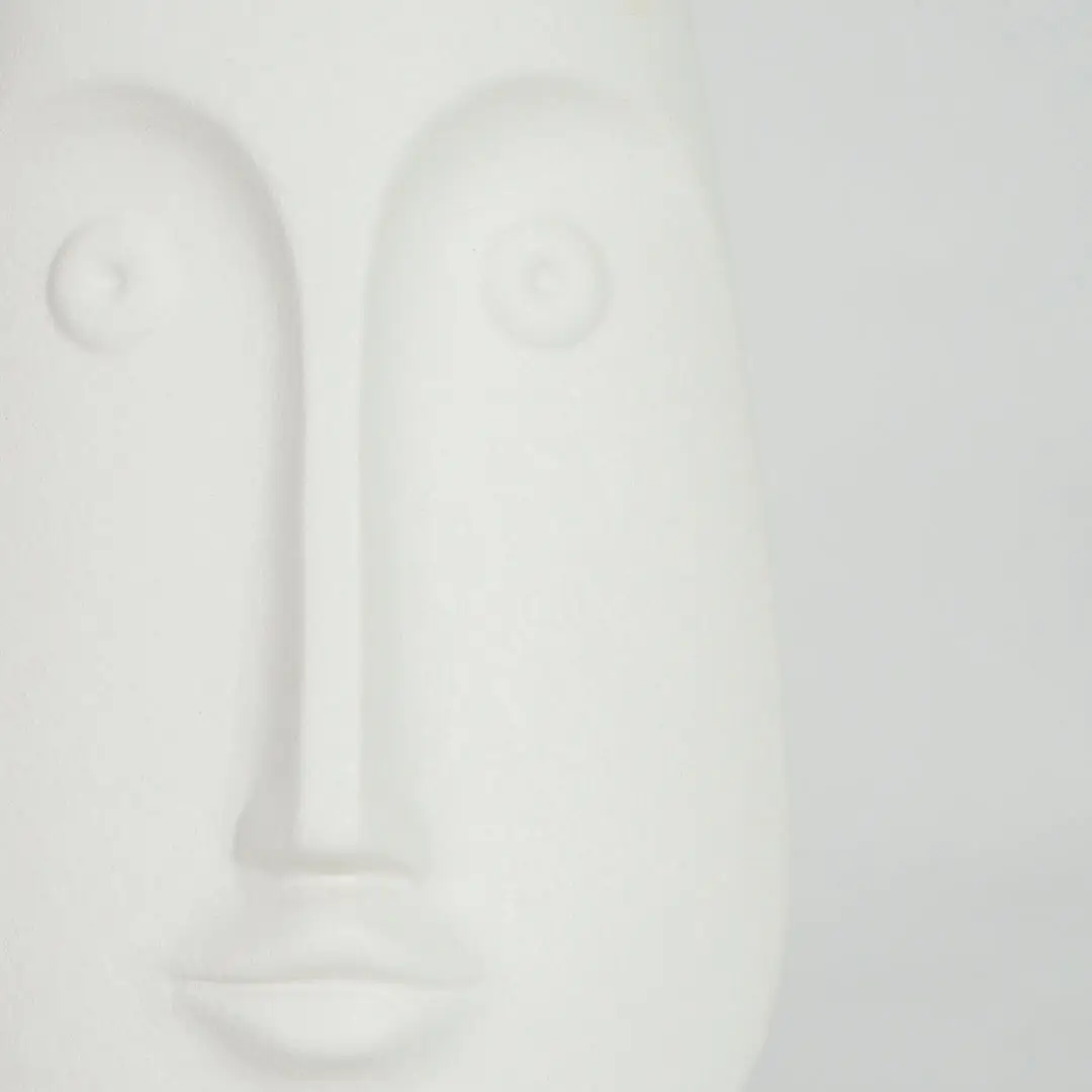 Closeup image of white ceramic abstract face sculpture for modern shelf decor styling with smooth matte finish.
