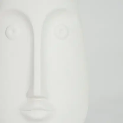 Closeup image of white ceramic abstract face sculpture for modern shelf decor styling with smooth matte finish.