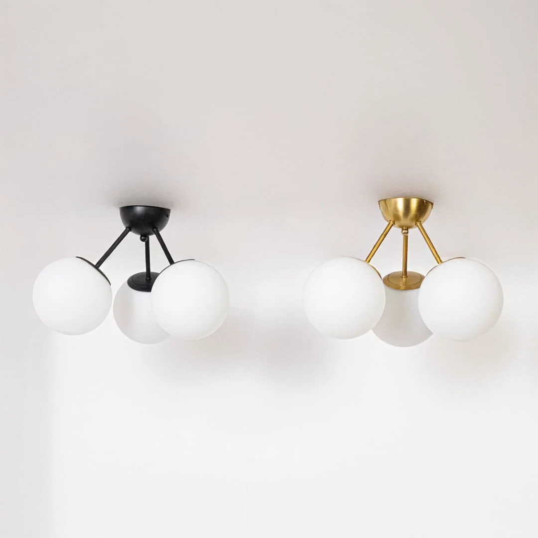 Black and gold ceiling lights with frosted glass globes displayed in off mode on white background for modern home decor.