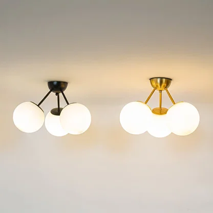 Black and gold ceiling lights with triple frosted glass globes glowing on white background for stylish home ceiling decor.