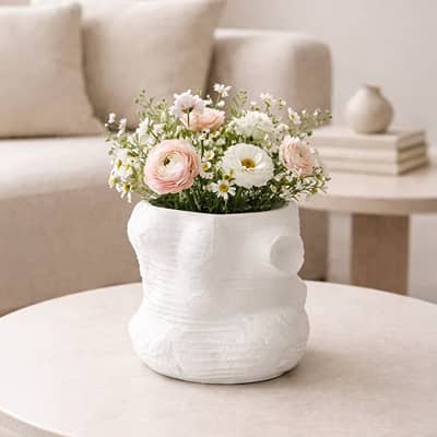 White ceramic sculpted decorative vase with blooms displayed on coffee table creating soft and refined interior decor accent.