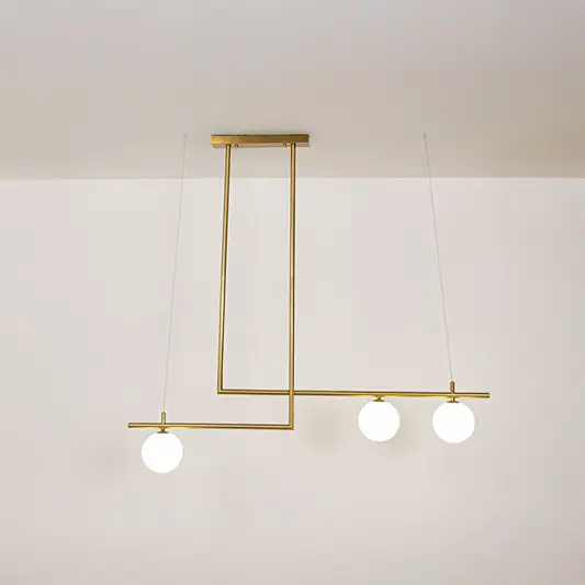 Gold metal chandelier with frosted glass globe shades and minimalist frame creating sophisticated modern ceiling lighting.