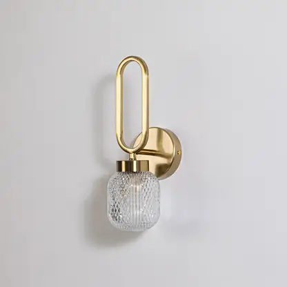 Minimalist gold wall sconce with loop frame and textured glass shade switched off displayed on plain white background for product use.