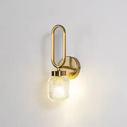 Modern wall light with gold metal frame and round glass bulb on neutral background minimal stylish lighting ideal for bedroom and living space decor.