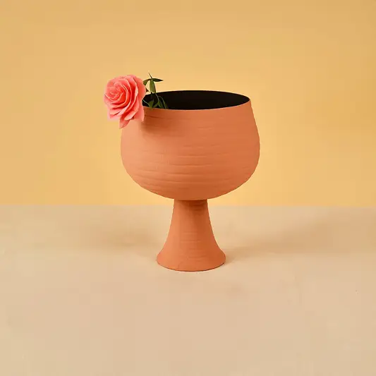 Terracotta metal pedestal bowl decor styled in a warm modern room adding an earthy accent to living room tables and shelves.