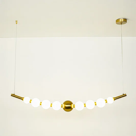 Minimal gold pendant light with white globe shades arranged in linear design on clean neutral background ideal for contemporary home lighting.