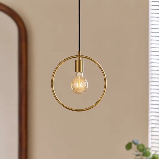 Gold metal ring pendant light with exposed bulb creating warm ambience in contemporary interiors.