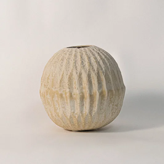 Textured ceramic vase in beige finish with ribbed pattern for table decor or shelf styling modern home placement white background.