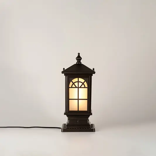 Vintage black outdoor gate light with warm glowing glass panels for elegant exterior decor use.