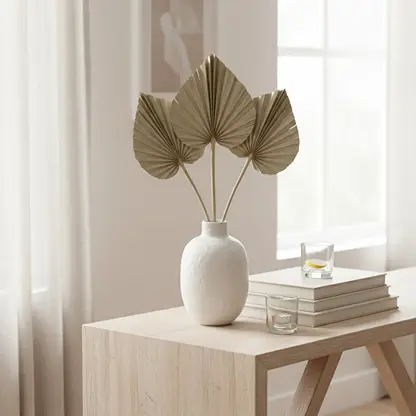 Three natural beige dried palm spear leaves arranged inside a white ceramic vase on a modern wooden entryway console table.