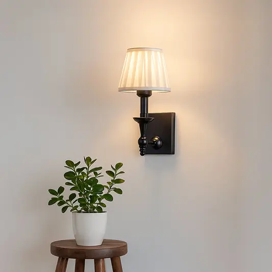 Black metal wall sconce with white pleated shade adding soft warm lighting to a modern elegant home interior.