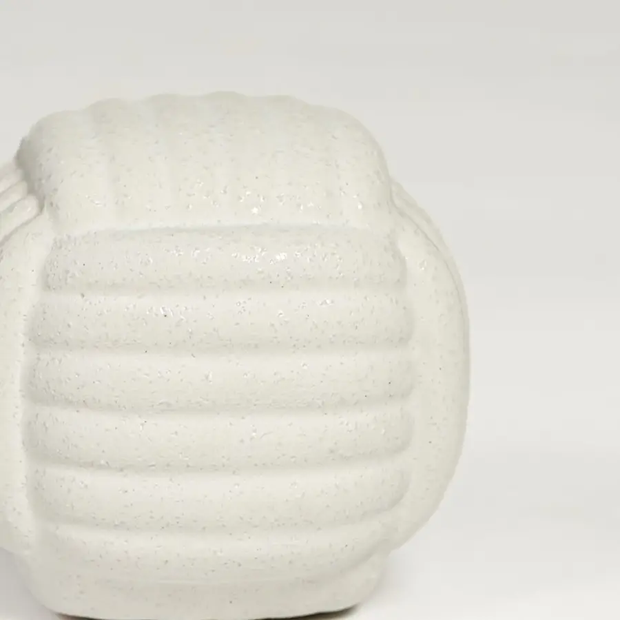 Close view of white ceramic textured decorative jar featuring rounded shape and subtle patterned surface.