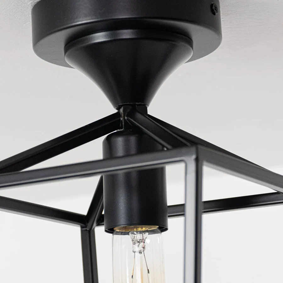 Closeup of black outdoor ceiling lantern highlighting the warm glowing bulb and clear glass cylinder designed for stylish exterior lighting.