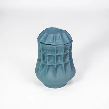 White background image of blue ceramic textured jar for modern tabletop decor styling with artistic matte finish.