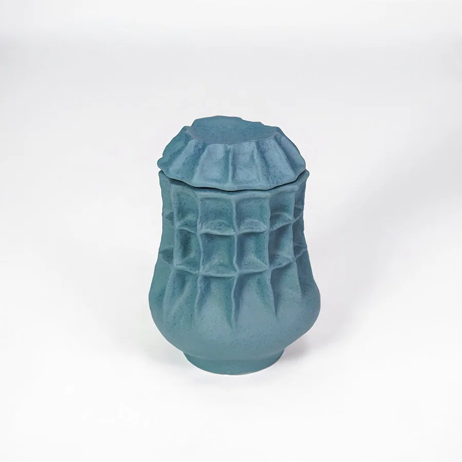 White background image of blue ceramic textured jar for modern tabletop decor styling with artistic matte finish.