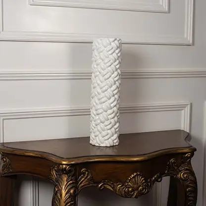 White ceramic cylinder vase with intricate braided rope texture displayed on a classic wooden console table for home decor.