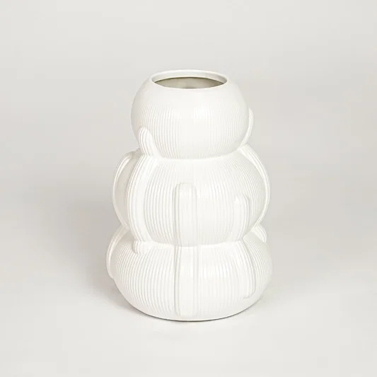 Closeup of glossy white ceramic vase with curved layered form ideal for elegant home decor shelf or side table styling.