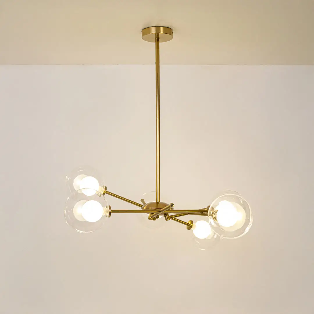 Gold metal chandelier with illuminated clear glass globe shades offering elegant contemporary ceiling lighting indoors.