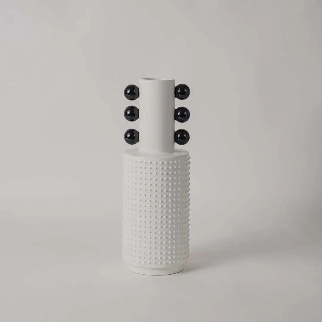 Minimalist white and black ceramic vase with glossy bowl design and ribbed column base on white backdrop.