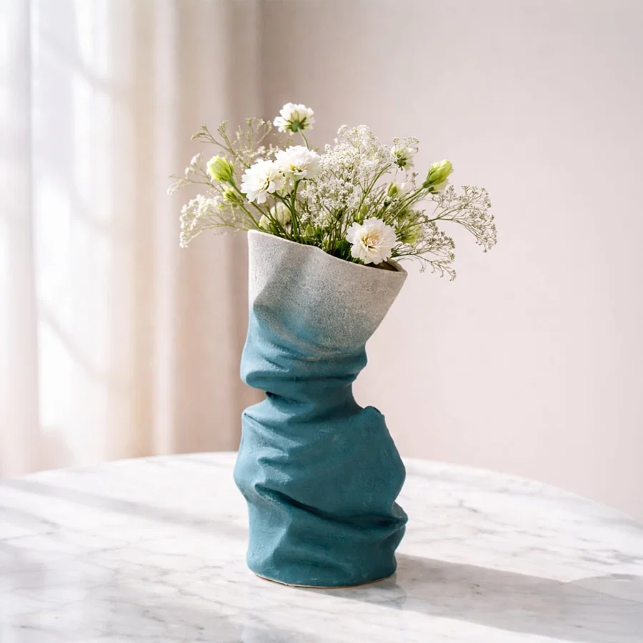 Blue ceramic flower vase with twisted textured design styled with fresh blooms for modern home decor placement.