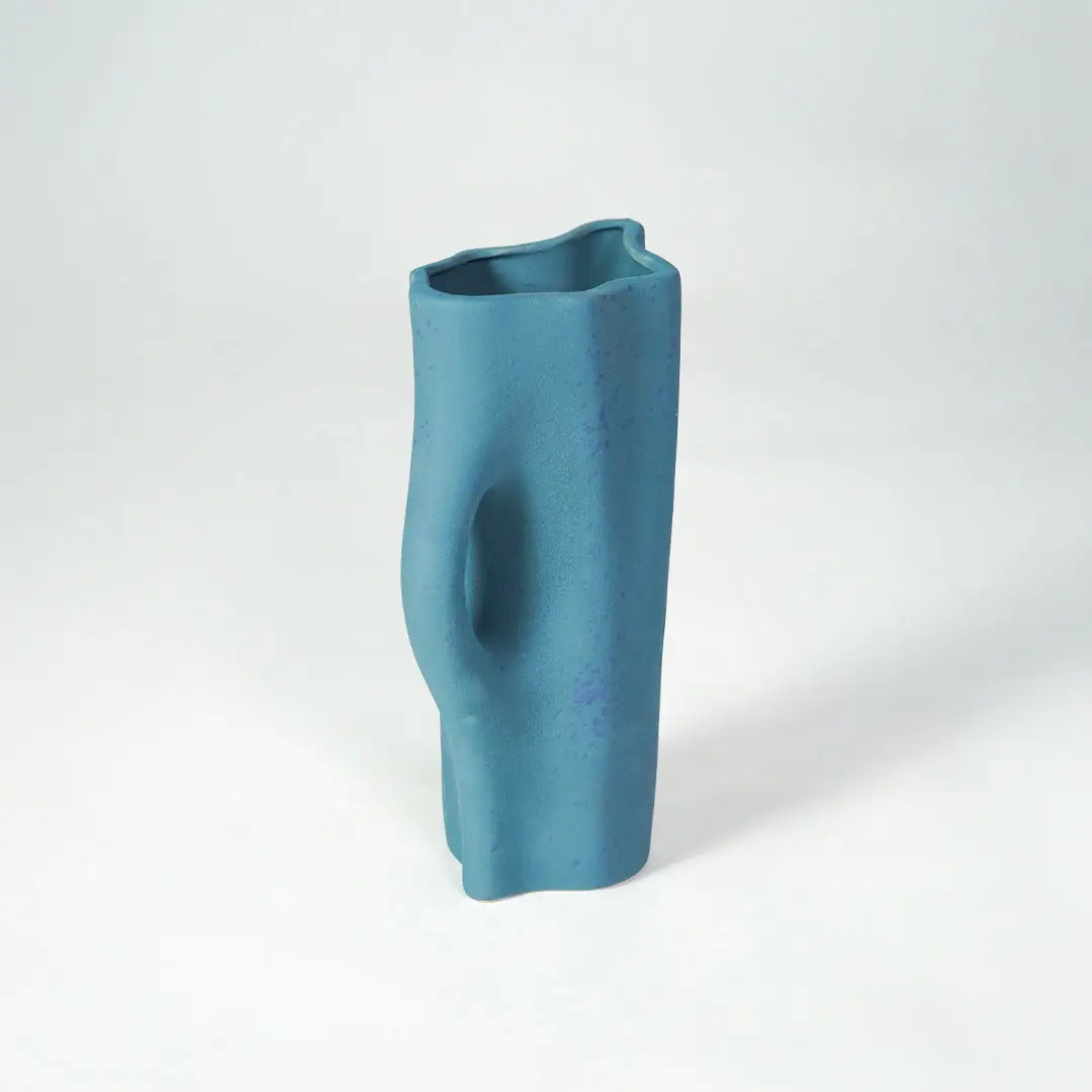 White background image of blue ceramic decorative vase for elegant shelf placement with textured matte finish.