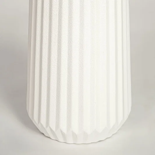 Closeup of matte white ceramic vase with fluted ribbed detailing ideal for elegant home decor shelf or side table styling.