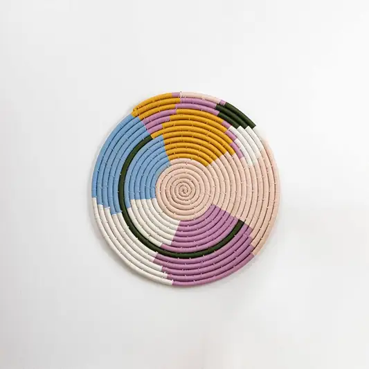 Round handcrafted pastel seagrass wall basket with purple blue cream and mustard pattern on white background image.