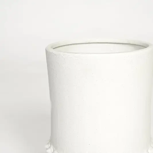 Detailed closeup of ceramic flower vase with raised textured pattern and solid tripod base in white finish.